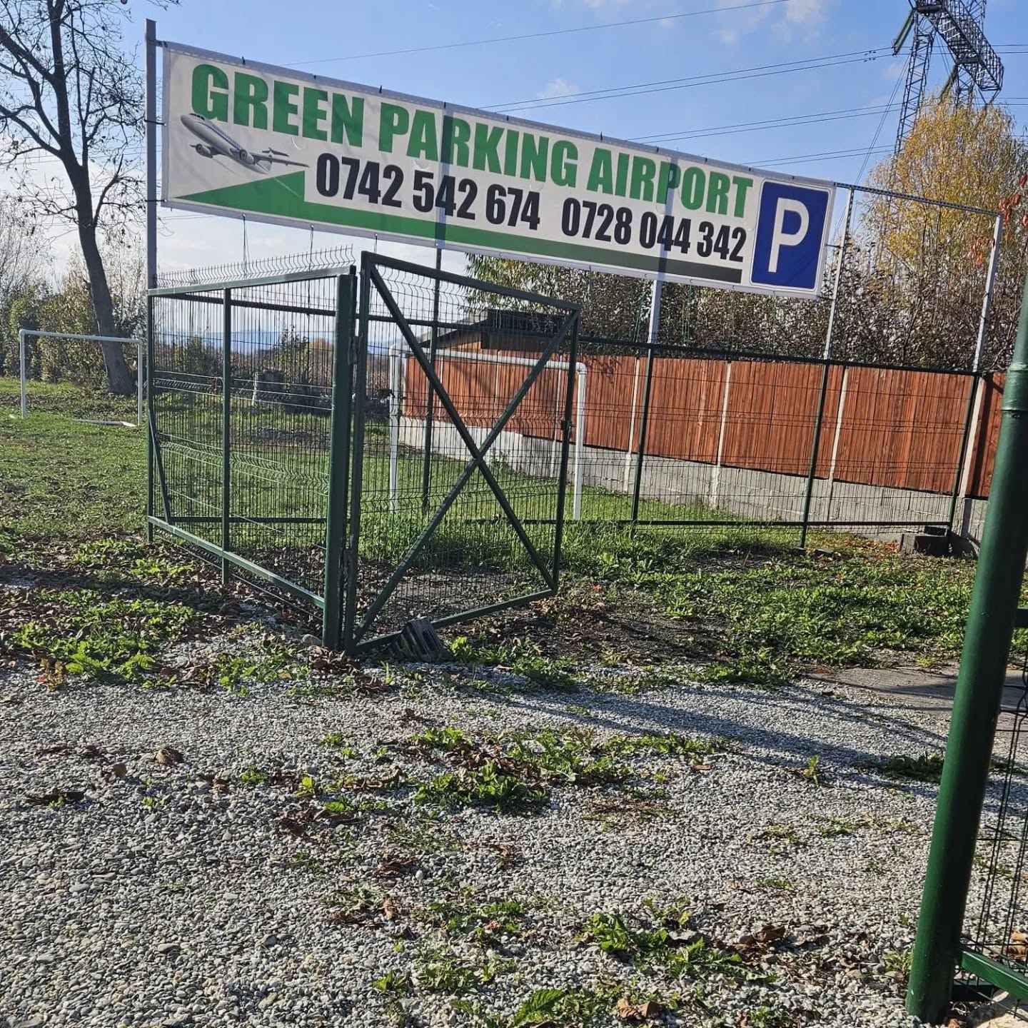 Intrarea parcării GreenParking Airport cu panoul și gardul verde